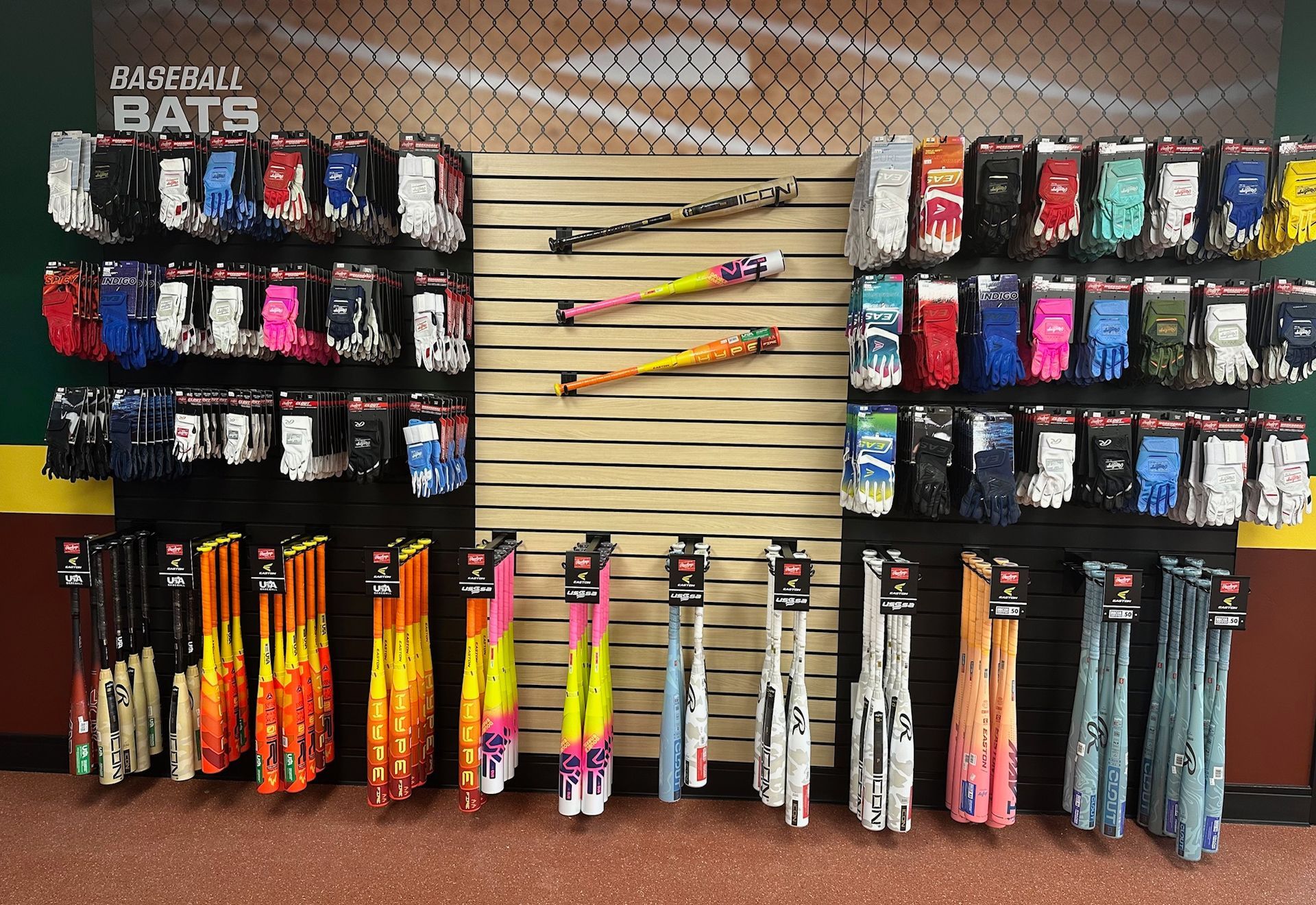 Display of colorful bats and bat accessories arranged on wall racks in a sports store