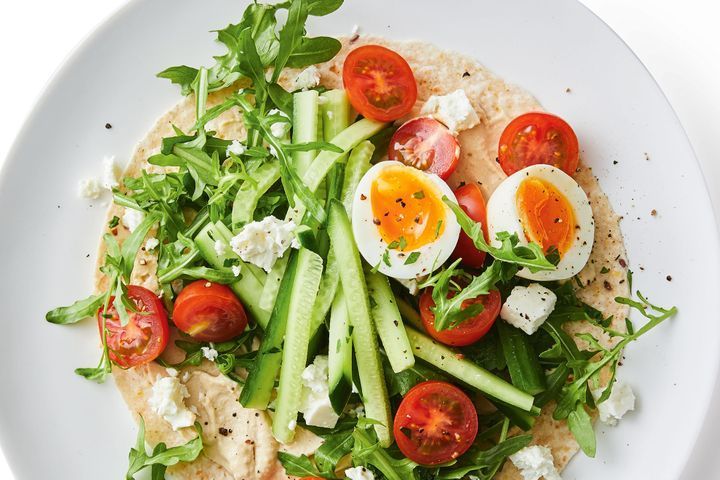 Flatbread topped with salad, egg and hummus ready to eat