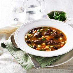 Bowl of steaming hot beef, barley and vegetable soup ready to eat