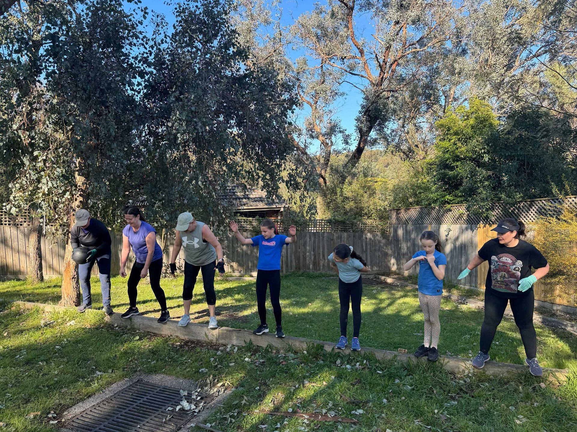 Members standing on balance beam passing weight bags between them
