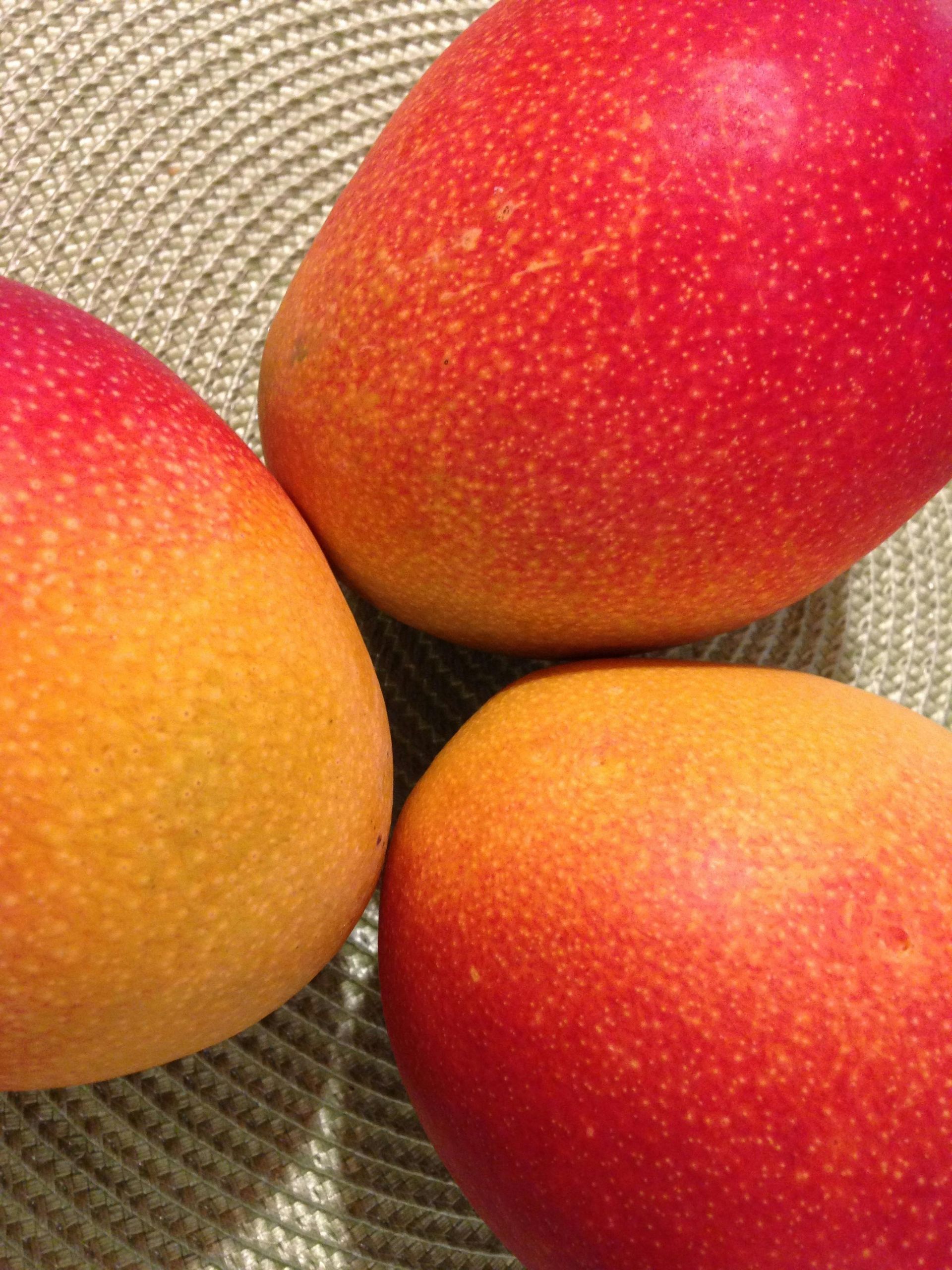 Three ripe mangos on a plate