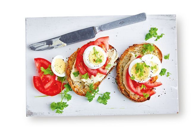 Toast with hummus, tomato and boiled egg on plate ready to eat