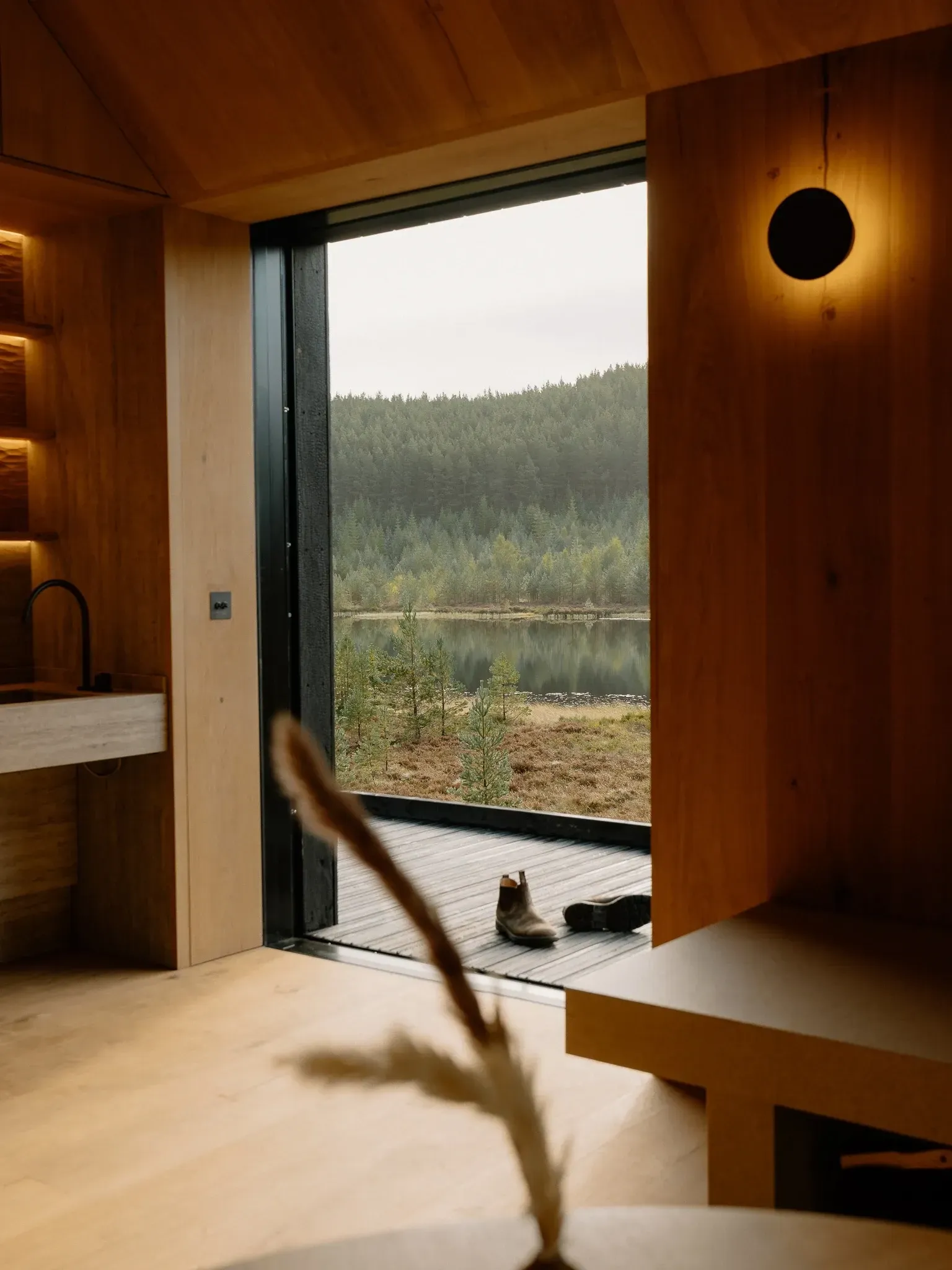 Floor-to-ceiling window at Moya Kabn overlooking the lochan and Cairngorms pine forest