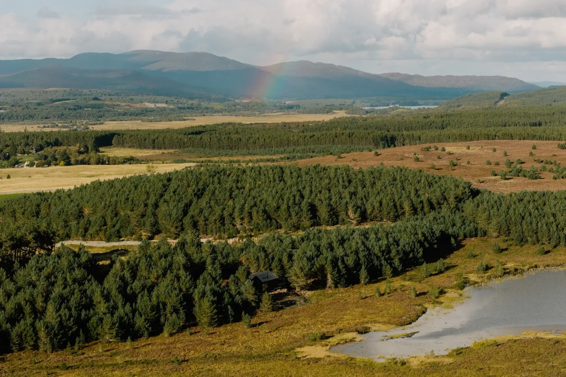 Aerial view of Cairngorms forests, Highland mountains and a rainbow near Moya Kabn