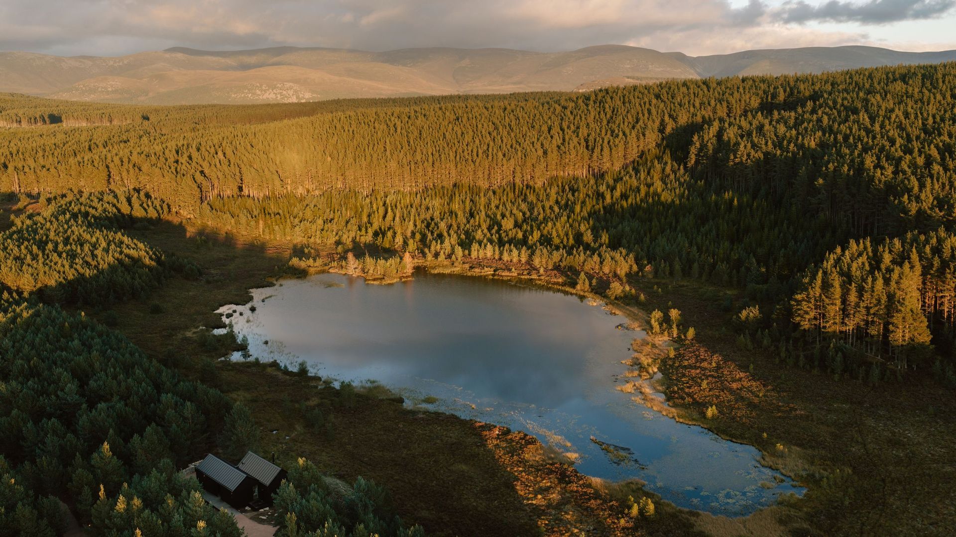Kabn: Moya Kabn, an architect-designed off-grid cabin beside a private lochan in the Cairngorms National Park, Scottish Highlands, at golden hour
