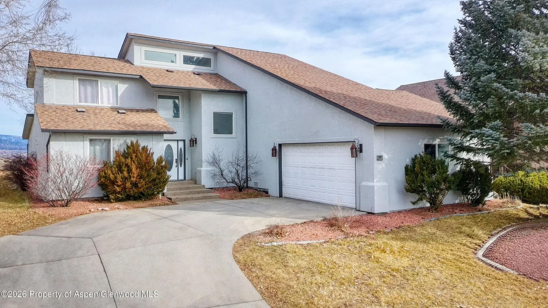 Suburban two-story house with white stucco walls, red-tile roof, garage, and curved driveway
