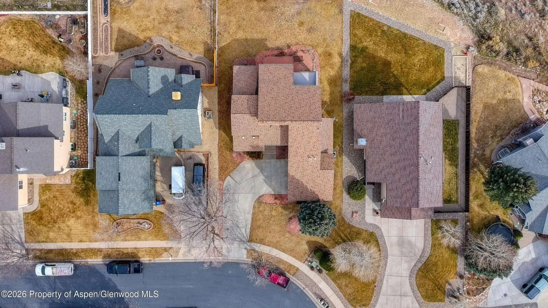 Aerial view of suburban houses with driveways, lawns, and a curving street.