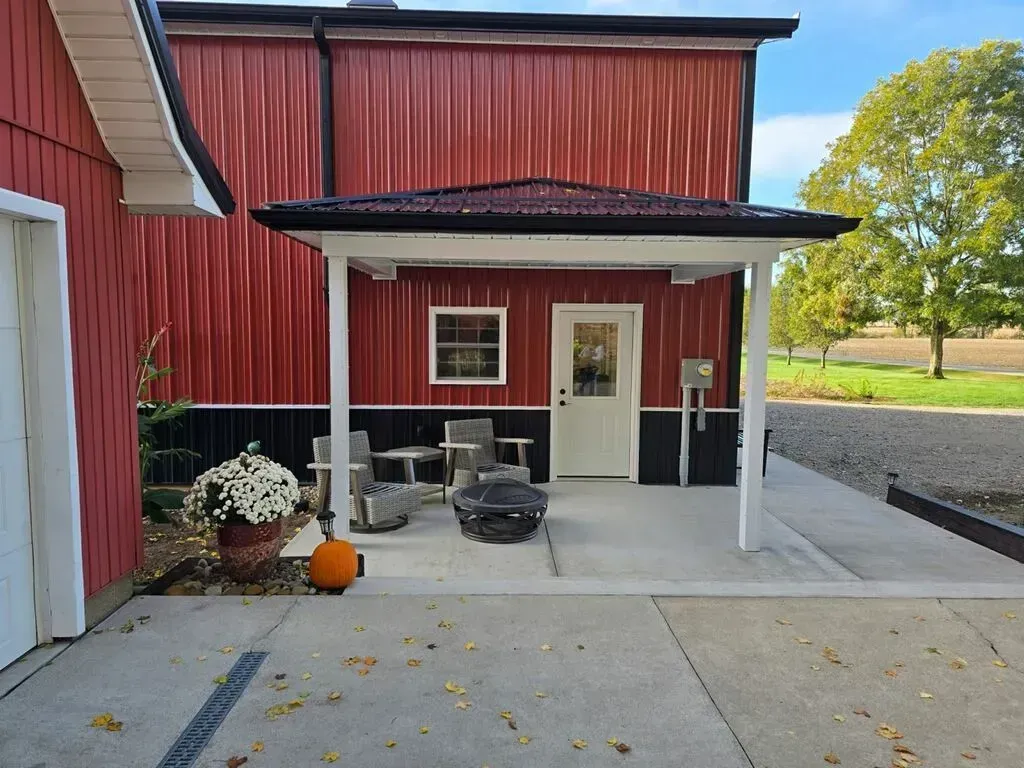 Red building with white-framed patio, chairs, and pumpkin. Red building with white-framed patio, chairs, and pumpkin.