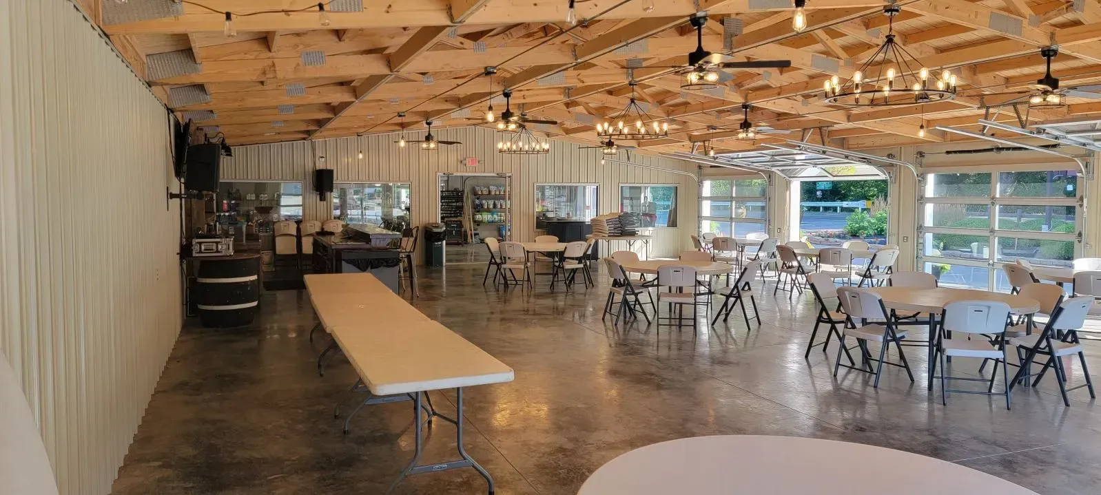 Event hall with tables, chairs, and string lights on a wooden ceiling. Event hall with tables, chairs, and string lights on a wooden ceiling.