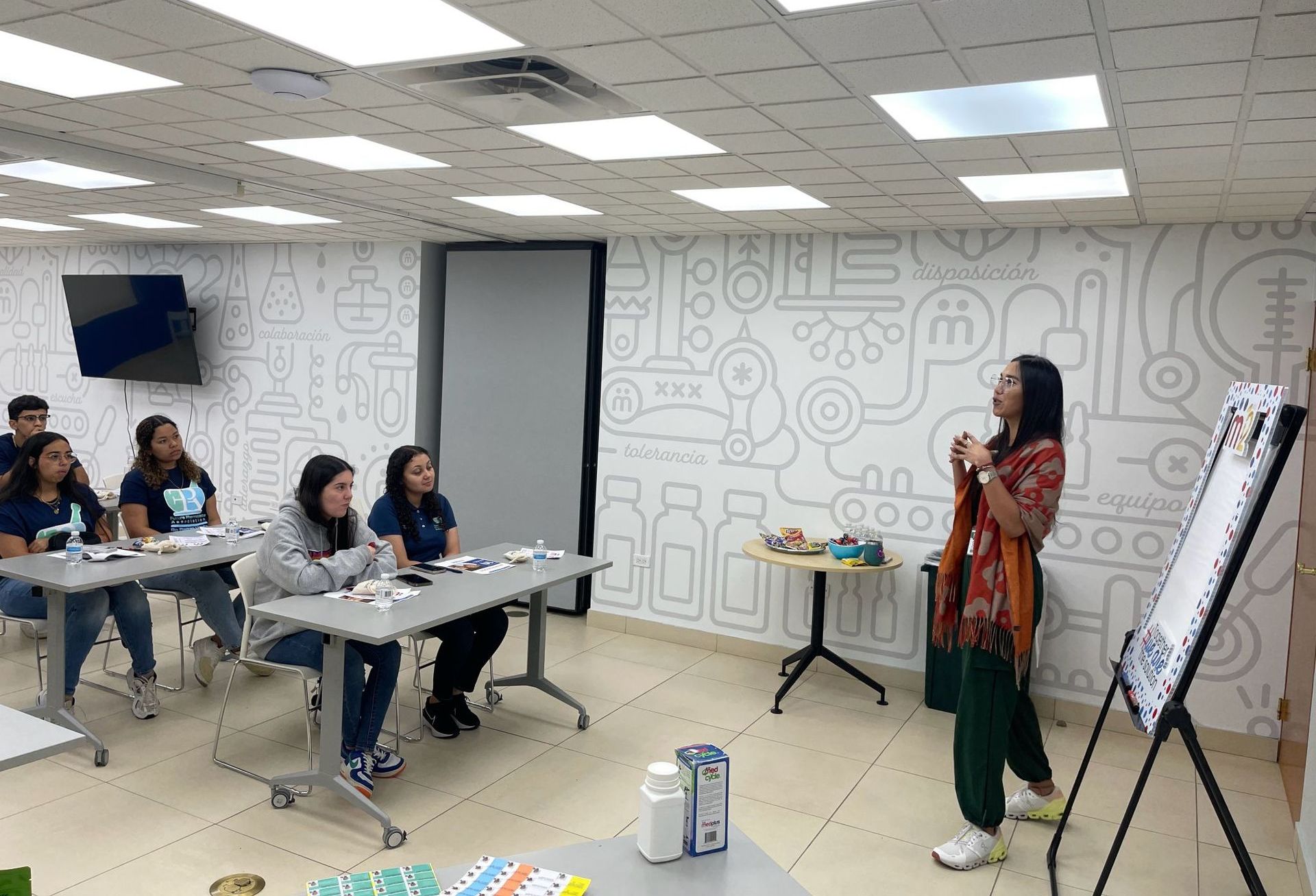 Una mujer está dando una presentación a un grupo de personas en una habitación.