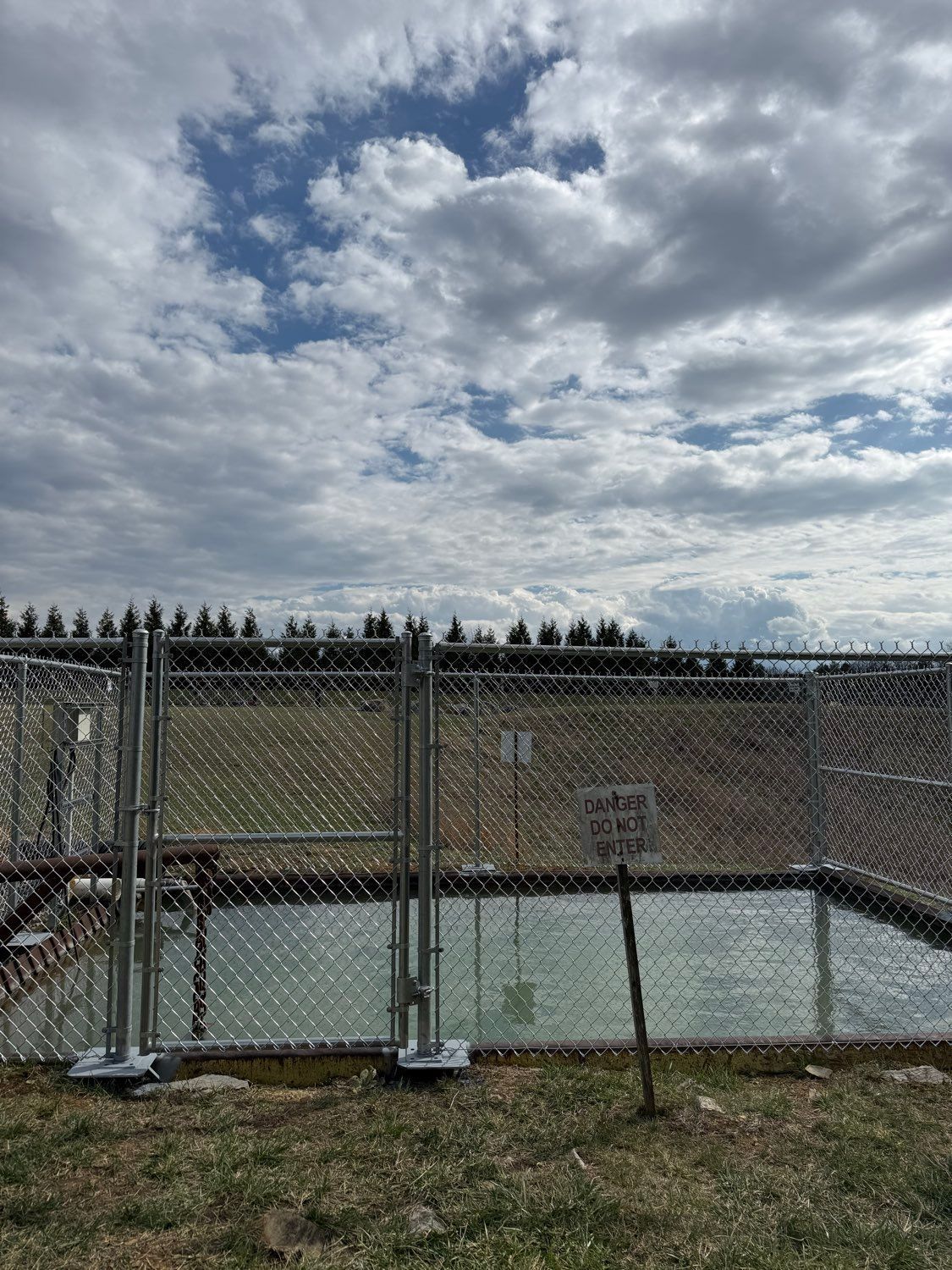 Chain-link fence around a fenced pool or court under a cloudy sky