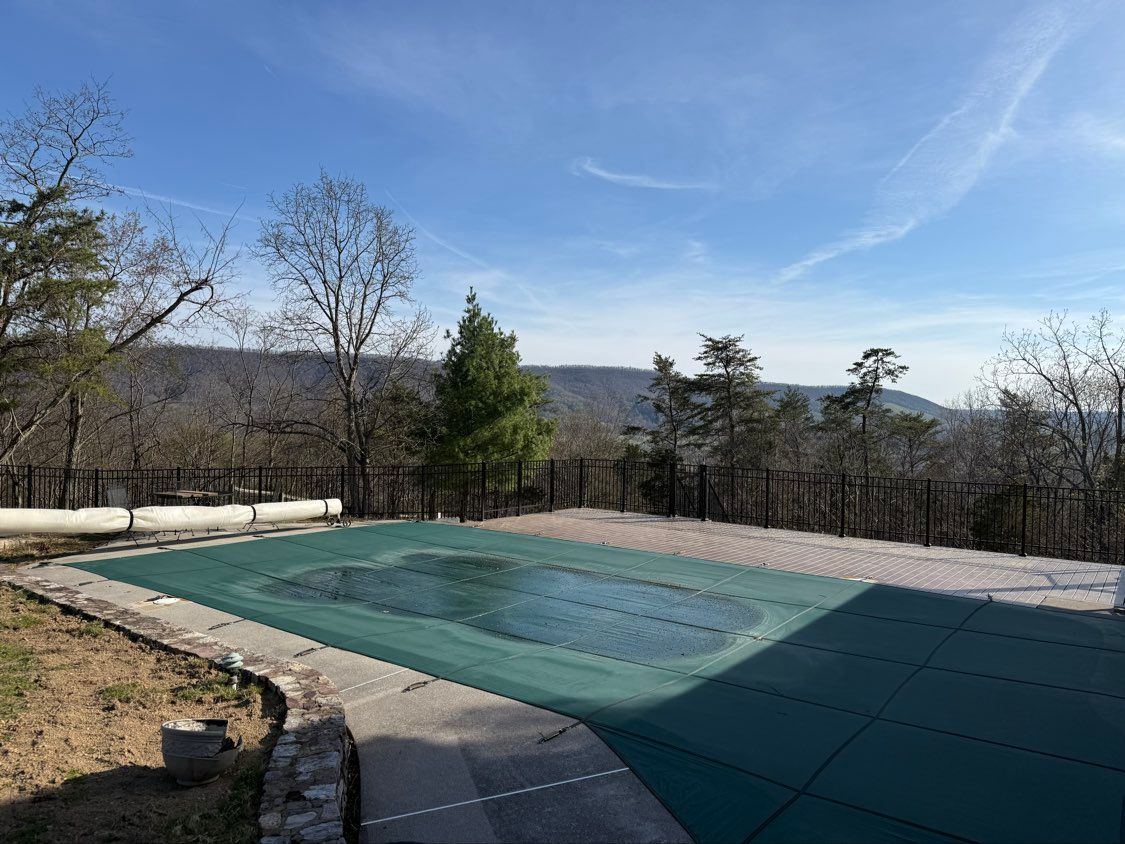 Outdoor covered swimming pool with a mountain view and bare trees under a clear blue sky