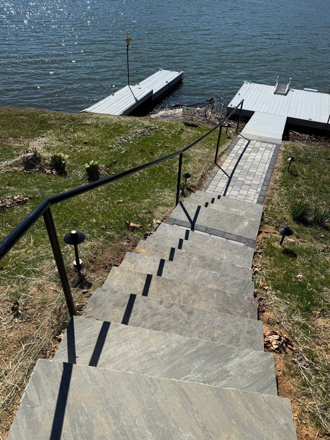 Steep stone steps with handrails leading down to a lakeside dock and platform.