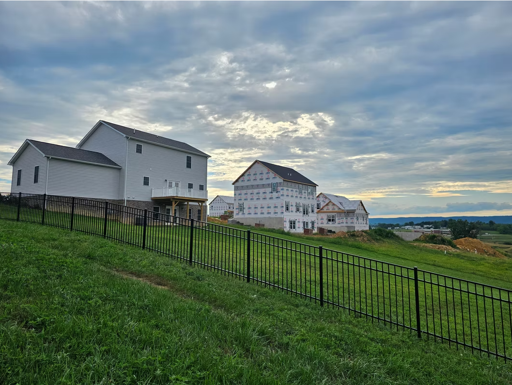 White houses on a grassy hillside under a cloudy sky at sunset
