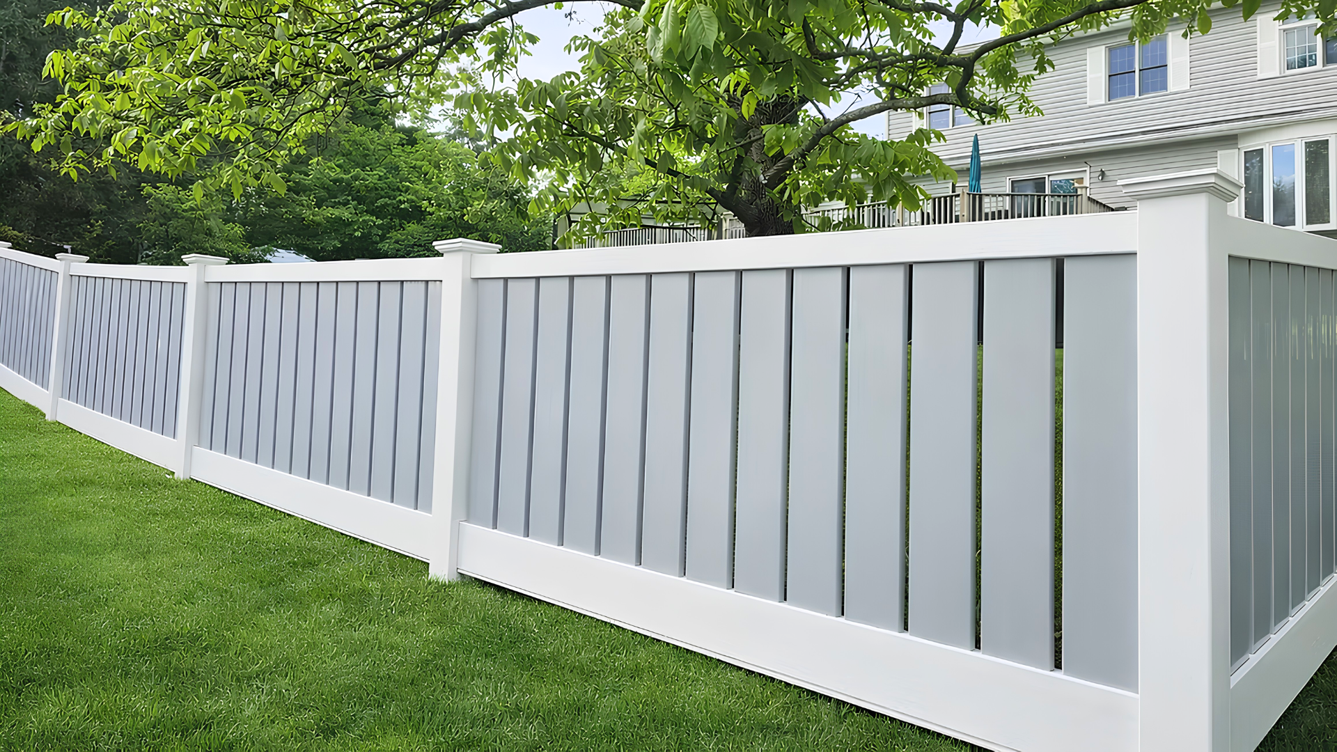 White vinyl fence with decorative diagonal panels along a green lawn in front of a house