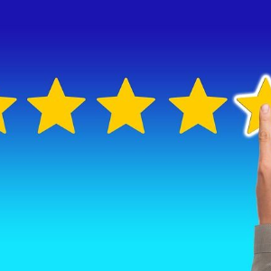 Five gold stars on blue background with a hand touching the fifth star