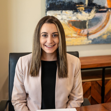 Corrine Curcio of Delaware Wealth Planners in a beige blazer seated in an office with abstract wall art behind her