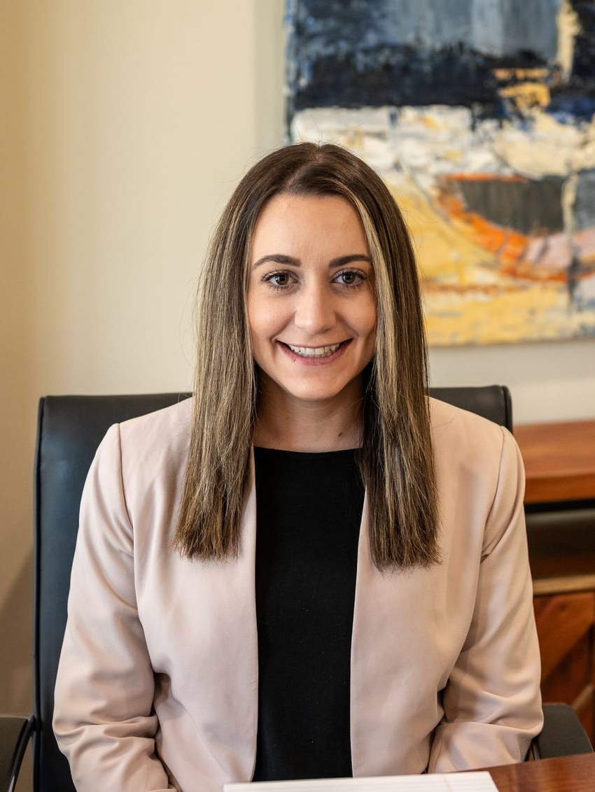 Corrine Curcio of Delaware Wealth Planners in a beige blazer seated in an office chair before abstract wall art