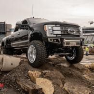 Black lifted pickup truck on rocks in a rugged outdoor setting