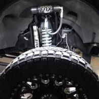 Close-up of a truck’s front suspension and large off-road tire inside the wheel well
