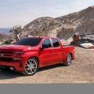 Red pickup truck parked on a rocky desert roadside with hills in the background