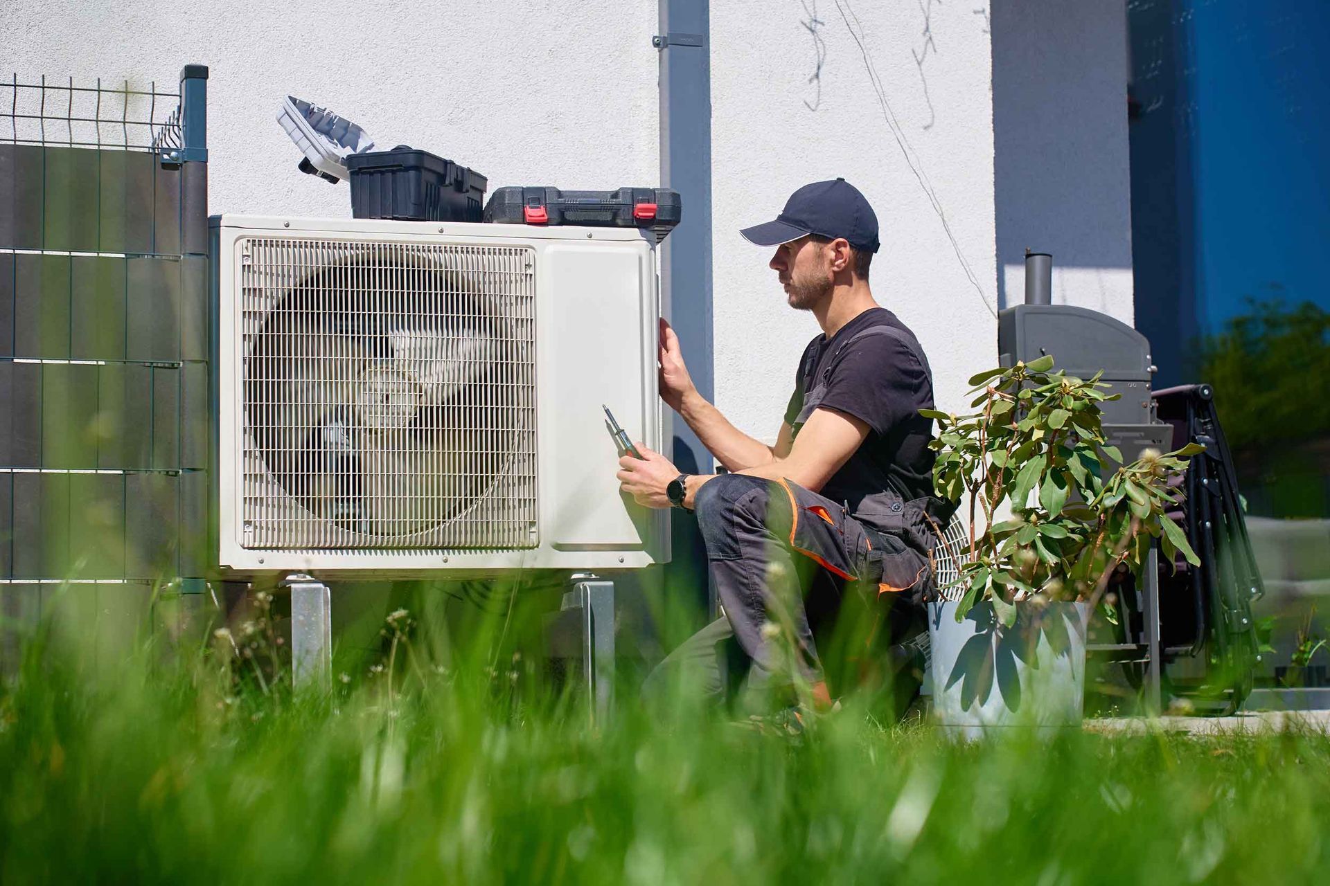 An air conditioning service contractor performs maintenance on an outdoor heat pump unit.