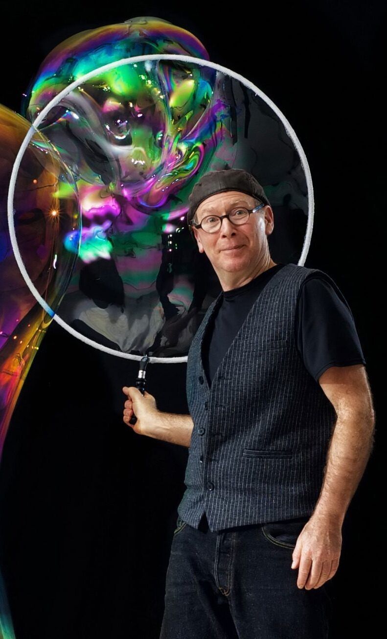 A man is standing in front of a large soap bubble.