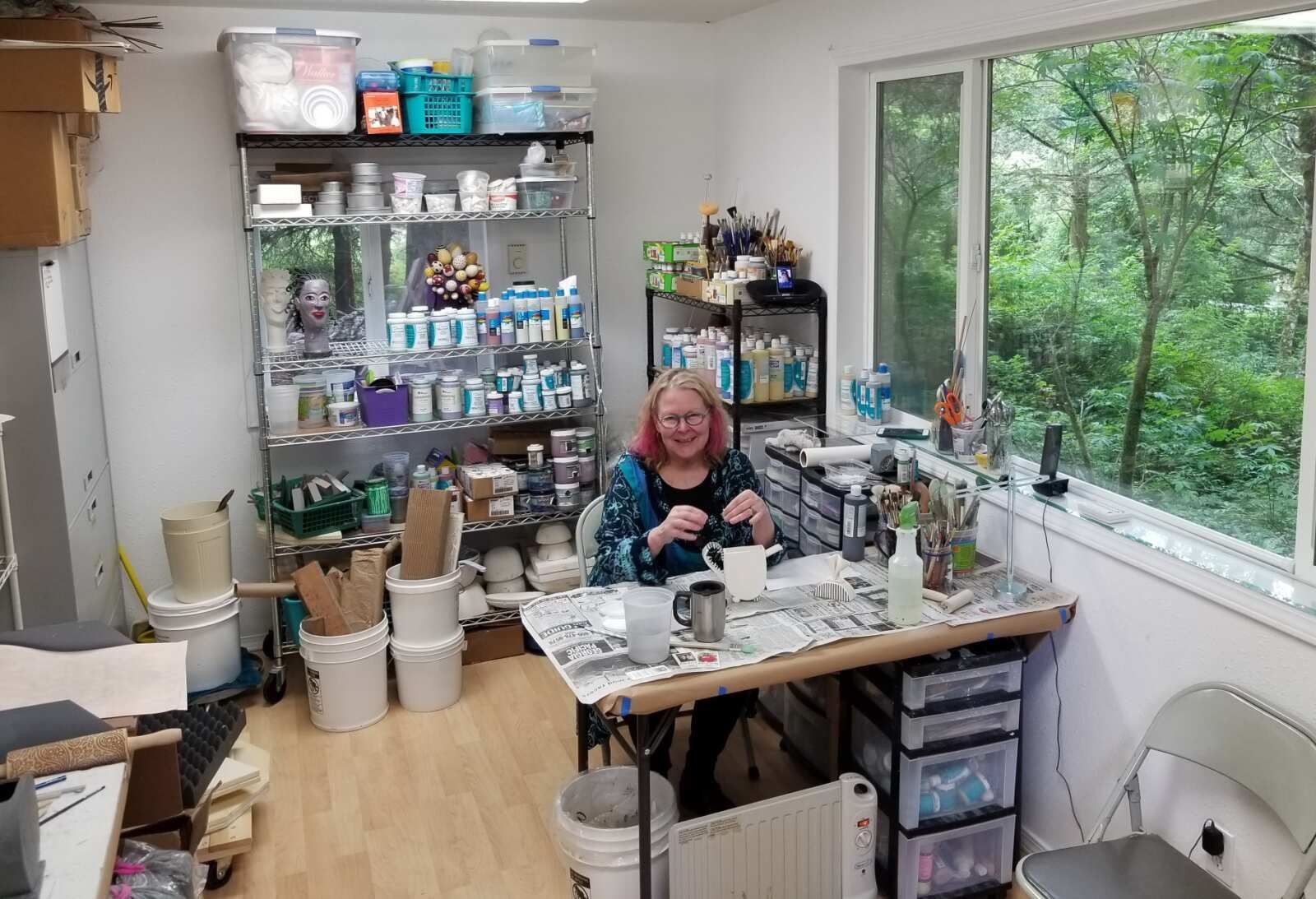 A woman is sitting at a table in a craft room.