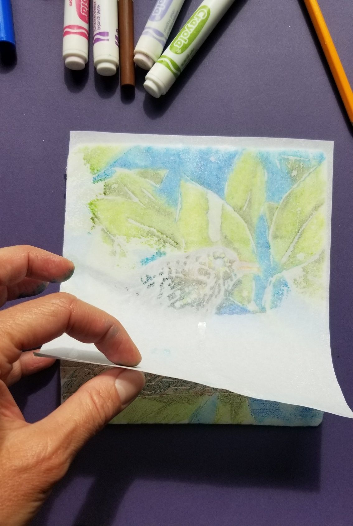 A person is holding a piece of paper with a painting on it