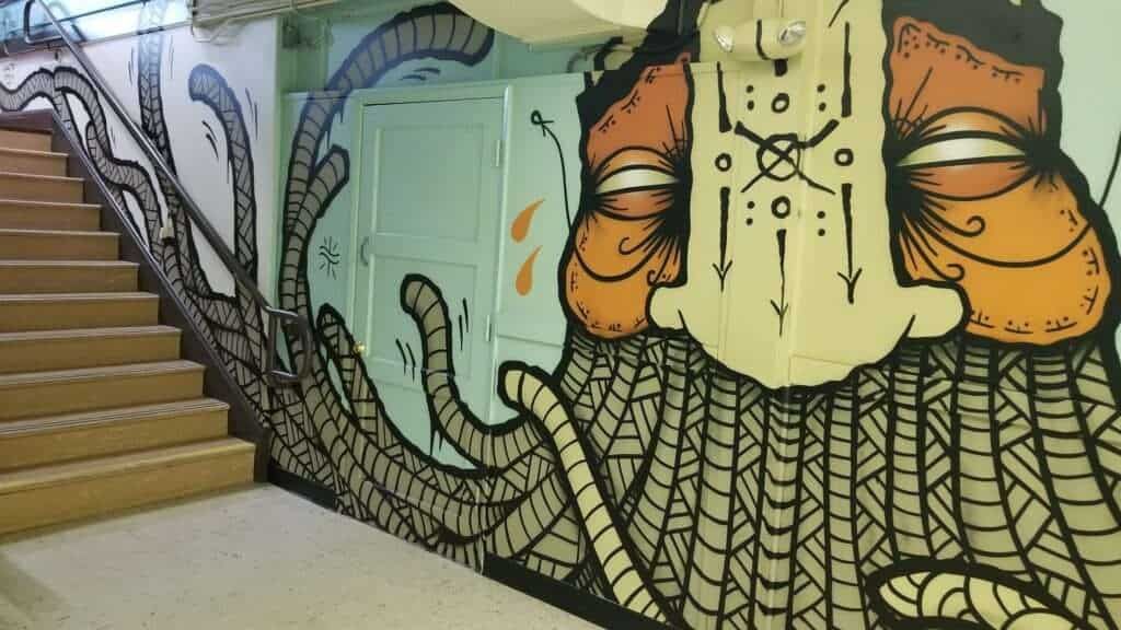 A staircase with a painting of a face on the wall