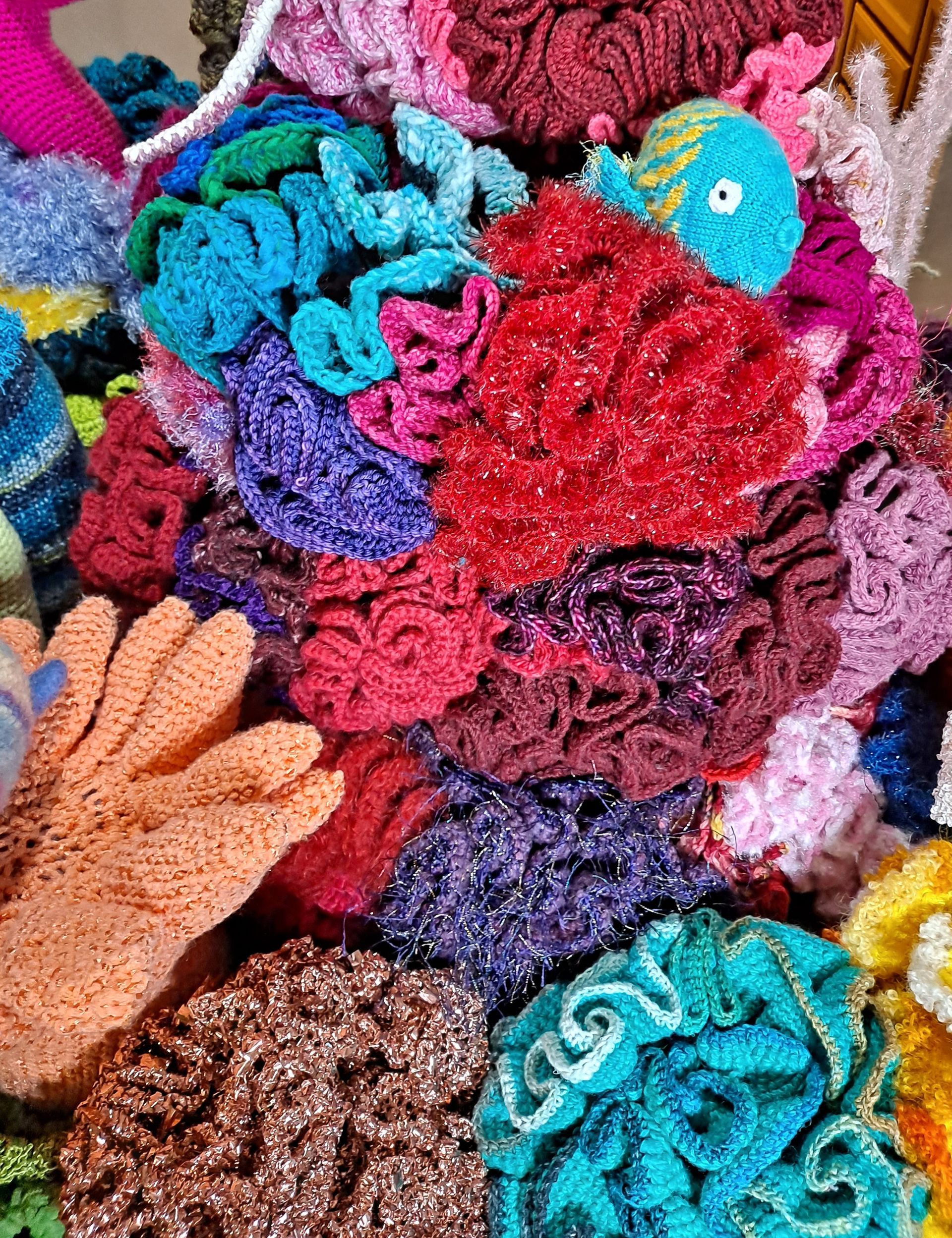 A pile of colorful crocheted corals with a fish in the middle.