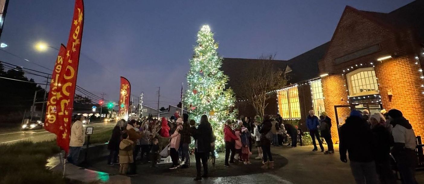 A group of people are standing around a christmas tree in front of a building.