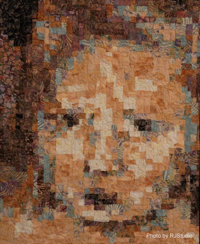 A quilt of a woman 's face made of pieces of fabric.