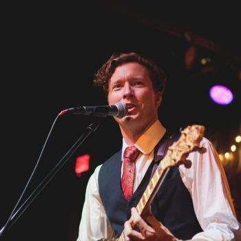 A man is singing into a microphone while holding a guitar.