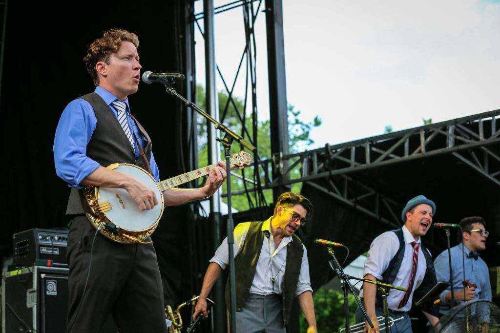 A man is playing a banjo on stage while another man sings into a microphone.