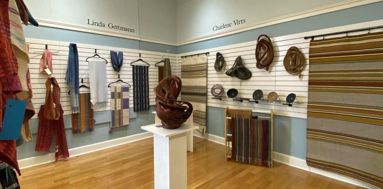 A room with a lot of clothes hanging on the wall and a statue on a pedestal.