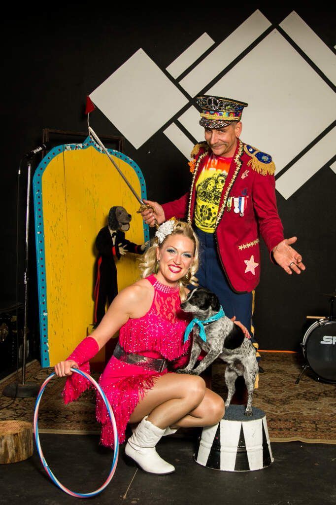 A man and a woman are posing for a picture with a dog and a hula hoop.