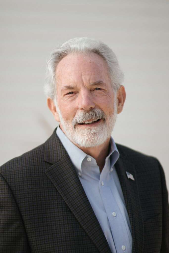 A man with a beard is wearing a suit and smiling.