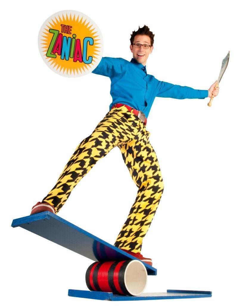A man in a blue shirt and yellow pants is balancing on a skateboard