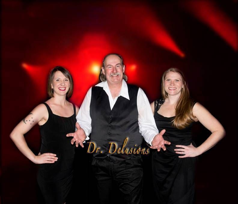 A man and two women are posing for a picture and the man is wearing a vest that says dr. dilsions