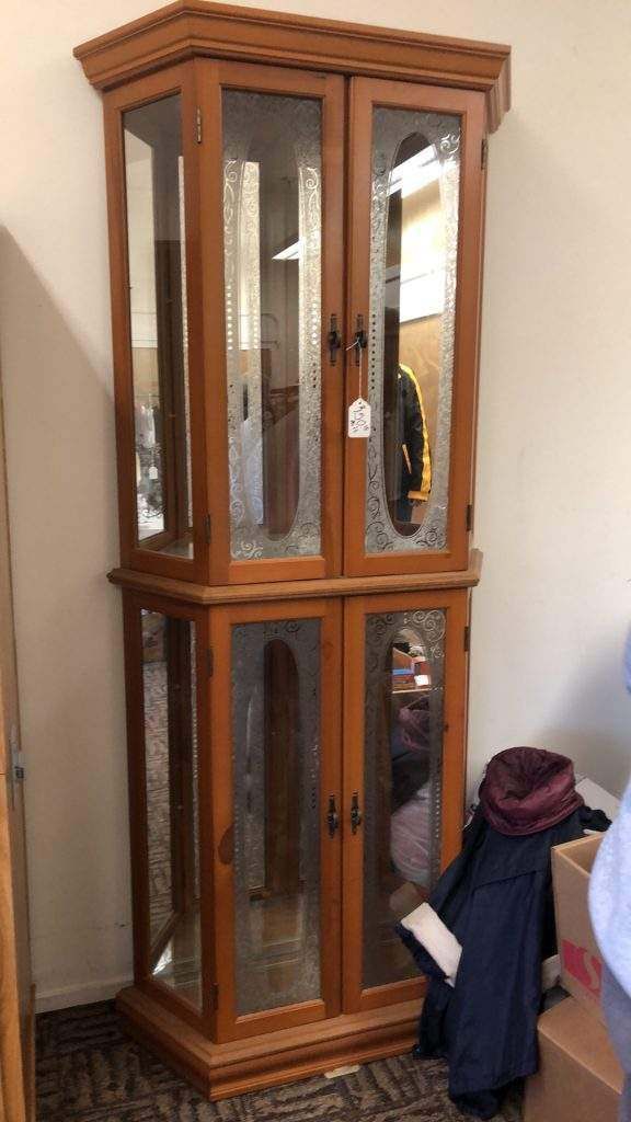 A wooden cabinet with glass doors is sitting in a room.