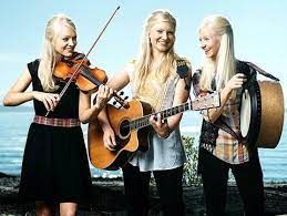 Three women are standing next to each other playing violins and guitars.