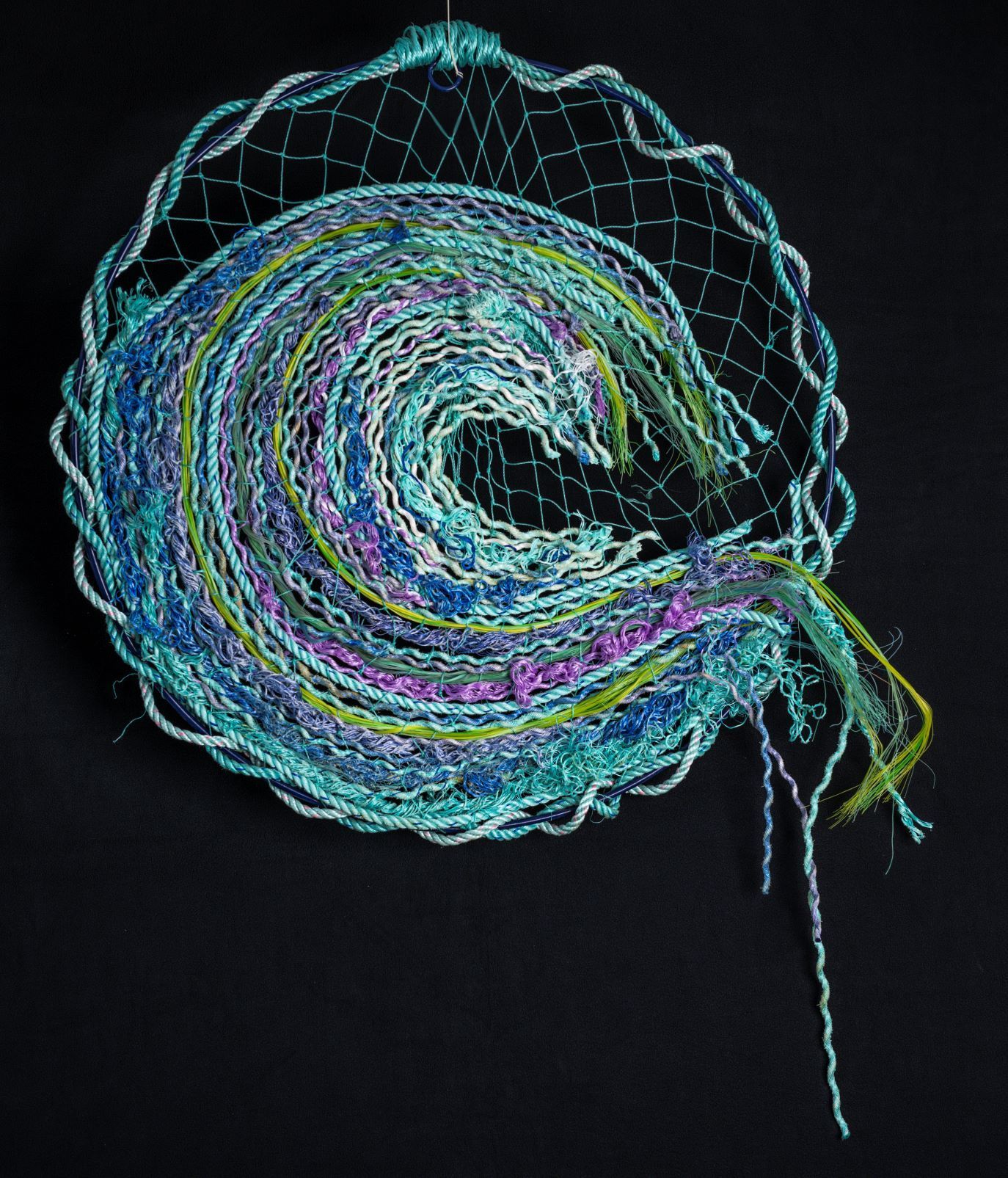 A blue and green yarn swirl on a black background