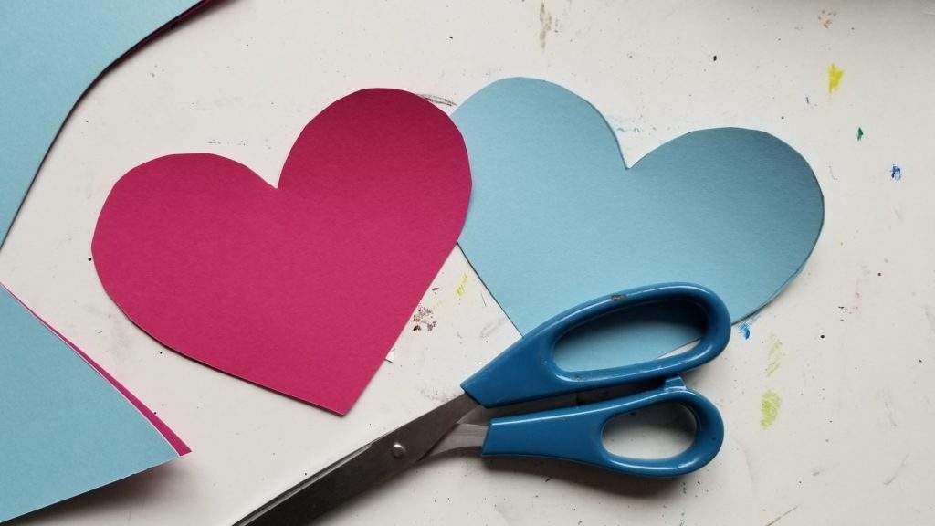 A pair of scissors next to two hearts on a table