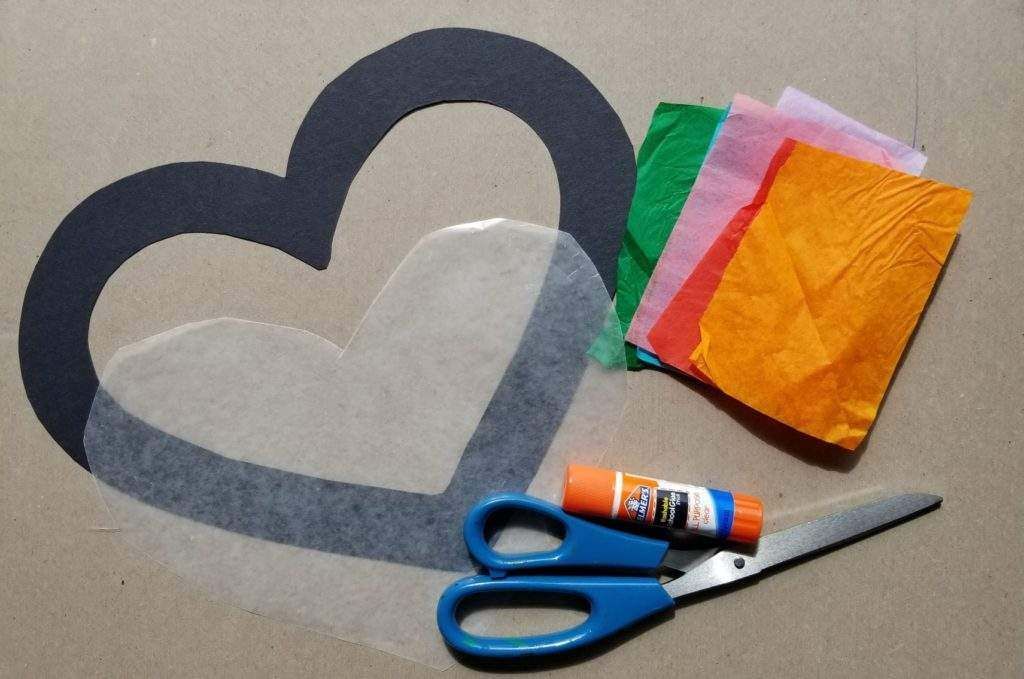 A pair of scissors next to a stick of glue