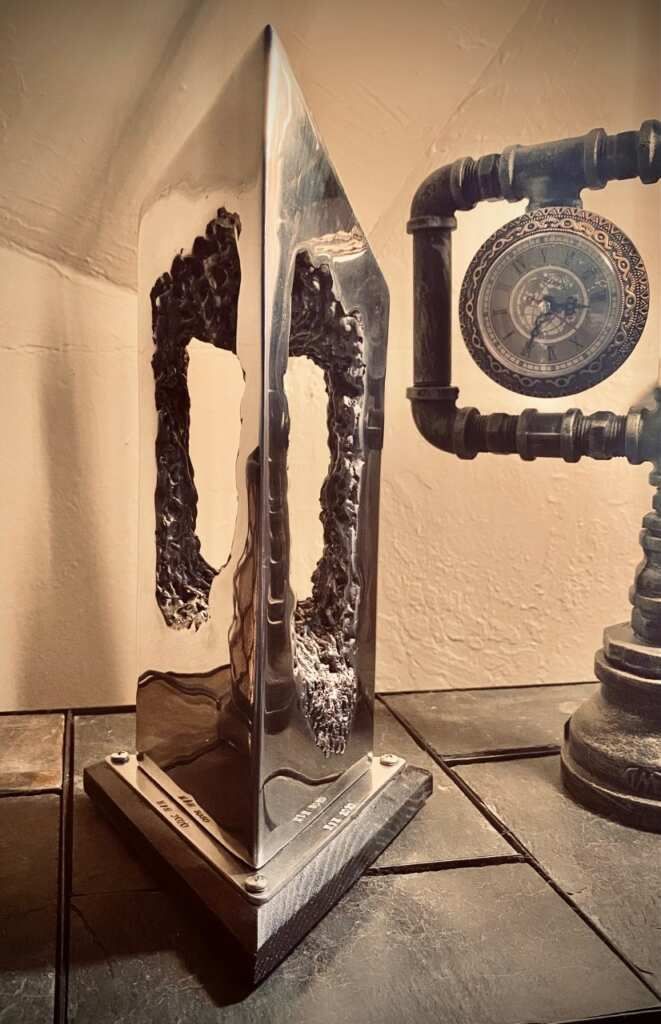 A sculpture is sitting on a table next to a clock.