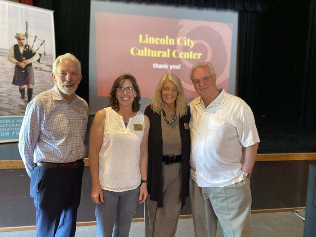 A group of people standing in front of a screen that says lincoln city cultural center