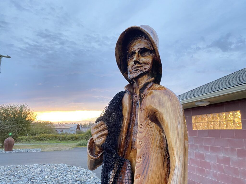 A wooden statue of a fisherman holding a fishing net.