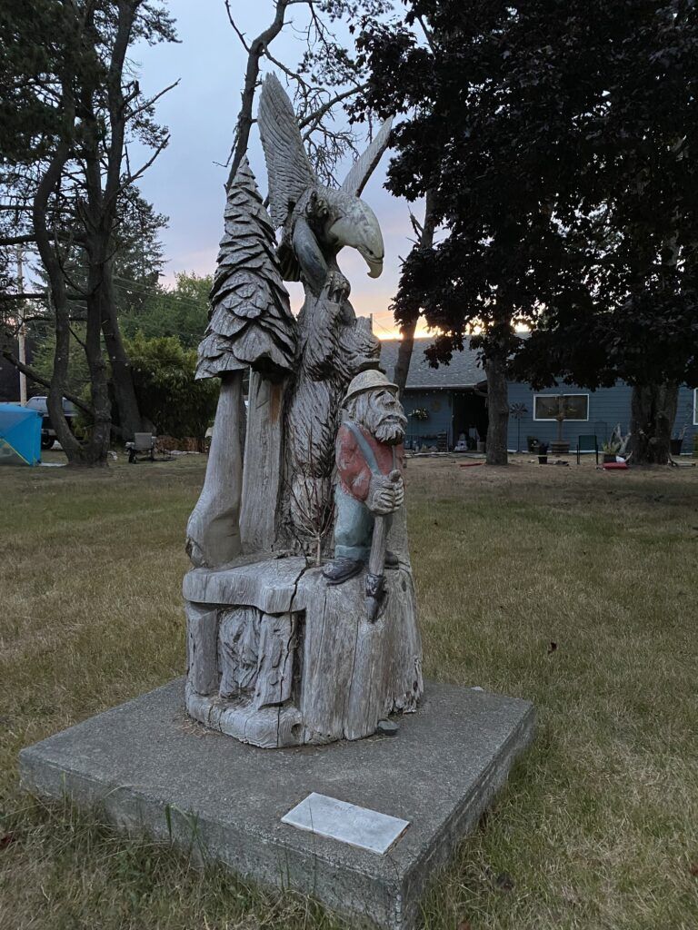 A statue of a man holding an eagle and a bear in a park.