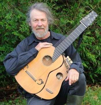 A man with a beard is kneeling down holding a guitar.